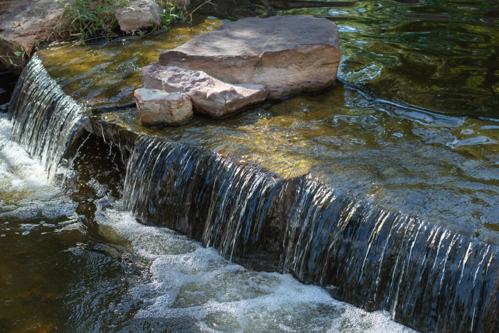 Water flowing over the rocky ledge of a garden pond