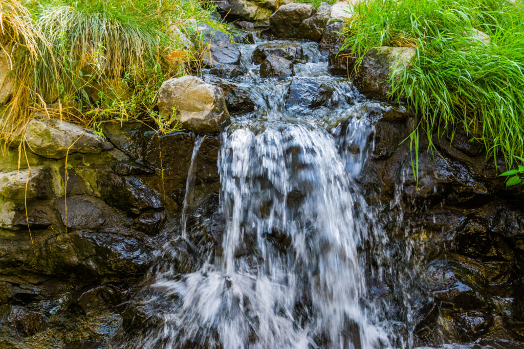 small streaming waterfall, water flowing over rocks, beautiful nature background